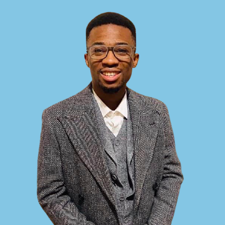 Adedeji Adegoke who is wearing a grey suit, glasses and is smiling.