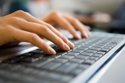 A person's hands on the keyboard of their laptop.