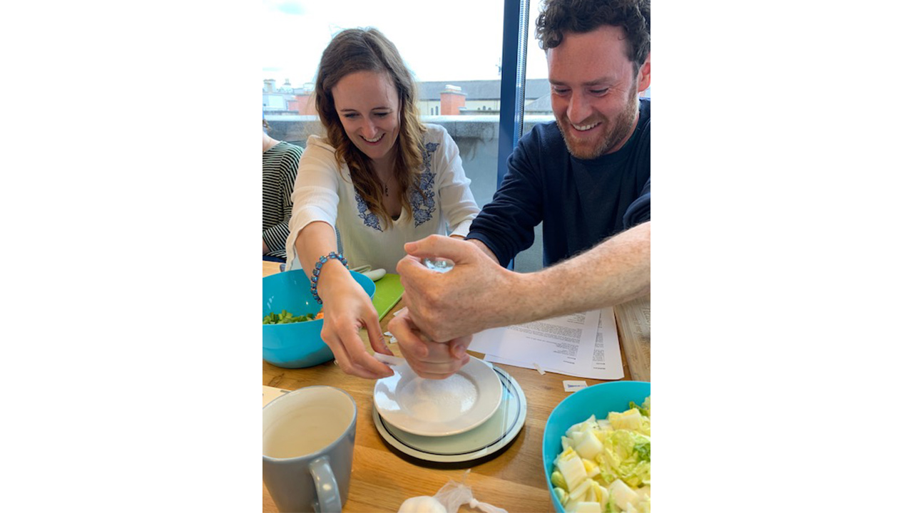 People sitting at a long table with plates and bowls of salad.
